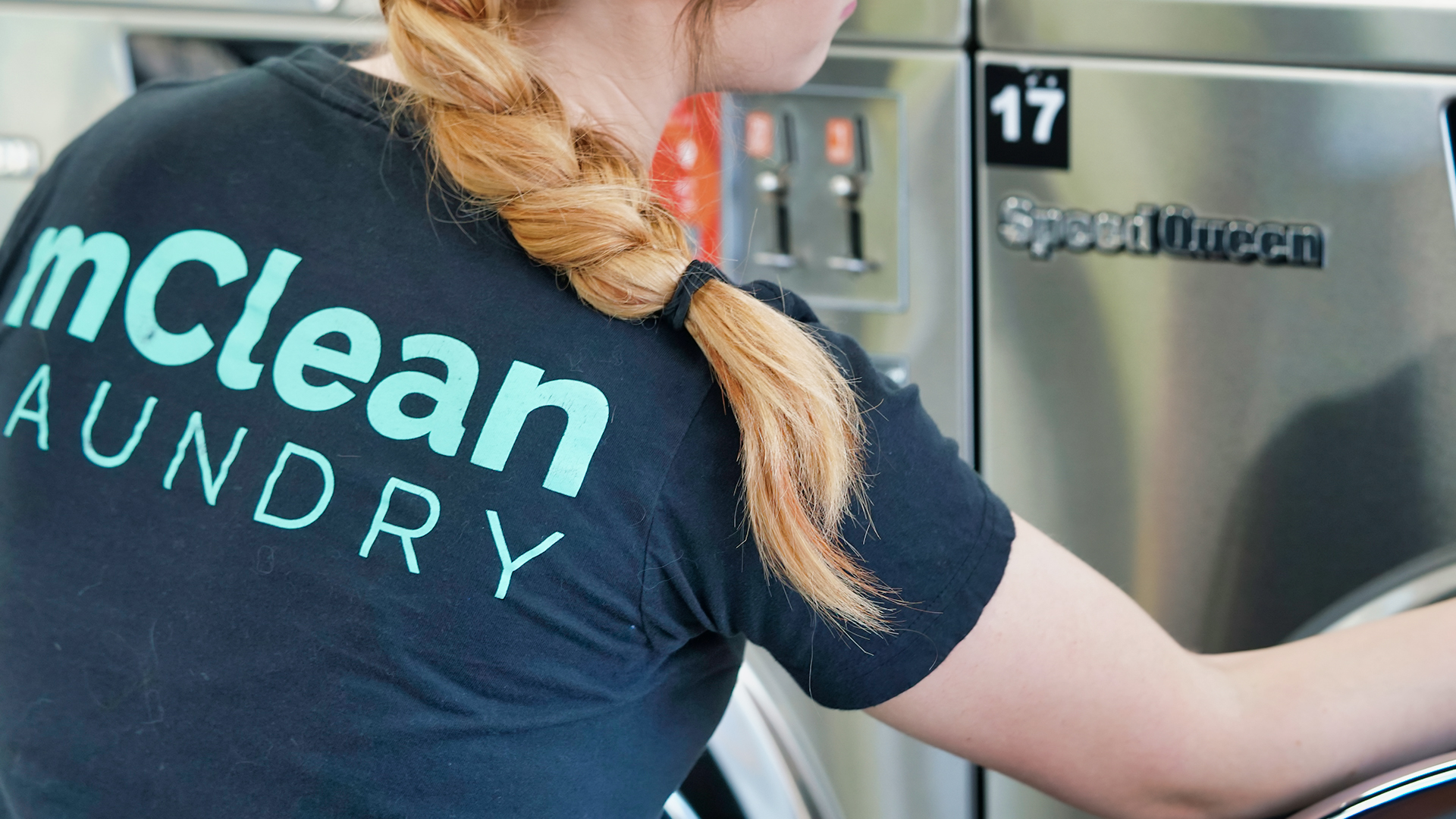 mClean Laundry employee adding customer clothes to laundry machine at the Rockwood or Flat Rock location